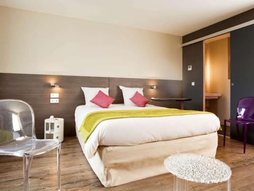 a bedroom with a large bed with pink pillows at ibis Styles Compiegne in Jaux