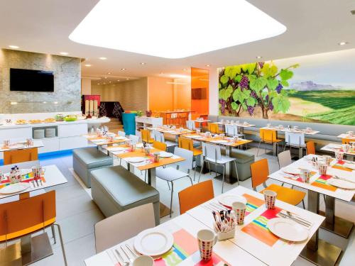 un restaurante con mesas blancas y sillas naranjas en Ibis Styles Madrid Prado en Madrid