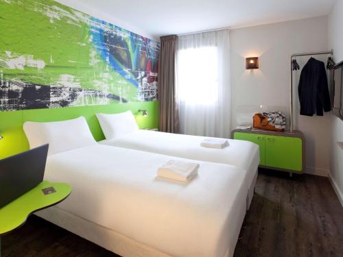 Cette chambre comprend un lit blanc et un mur vert. dans l'établissement Ibis Styles Lyon Villeurbanne Parc de la Tête d'Or, à Villeurbanne