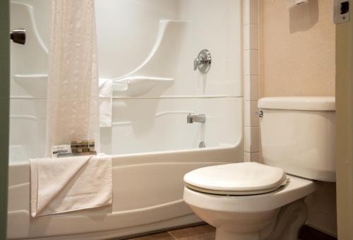 La salle de bains blanche est pourvue d'une douche et de toilettes. dans l'établissement Marmot Lodge Jasper, à Jasper