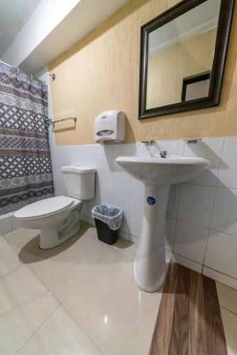 a bathroom with a sink and a toilet and a mirror at Hotel y Restaurante Castillo de los Altos in Quetzaltenango