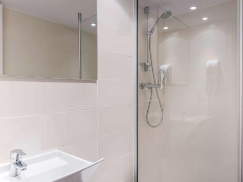 uma casa de banho branca com um chuveiro e um lavatório. em ibis Styles Paris Eiffel Cambronne em Paris