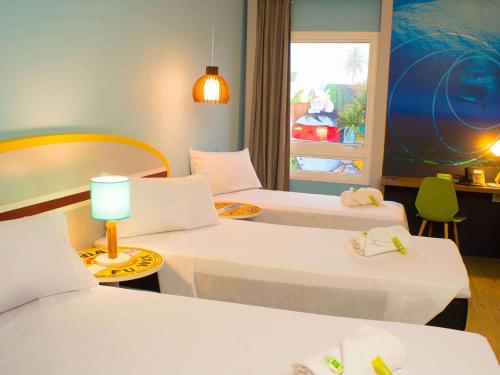 a hotel room with two beds and a window at Delphin Surf Hotel in Guarujá