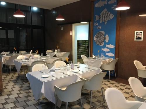 a dining room with white tables and white chairs at Flat em Ondina (ap.404) in Salvador