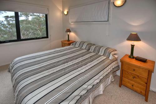 a bedroom with a bed and two lamps and a window at Delmonte in Medlow Bath