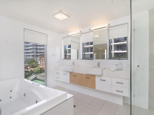 a white bathroom with two sinks and a shower at Maili 6 Luxury sky home in Gold Coast