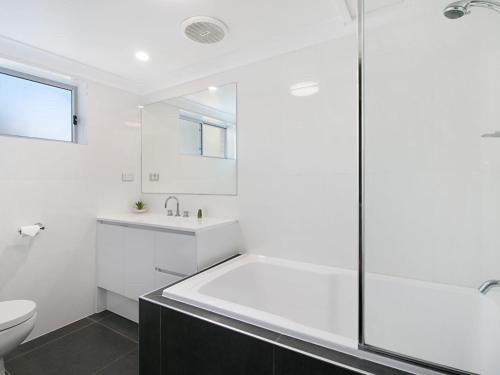 uma casa de banho branca com um chuveiro e um WC. em Maybury Unit 3 em Gold Coast