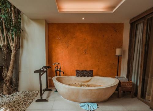 a bath tub in a room with a wall at Burasari Phuket Resort & Spa in Patong Beach