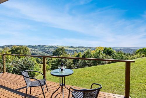 a table and two chairs on a deck with a view at Rosebrook Cottages in Maleny