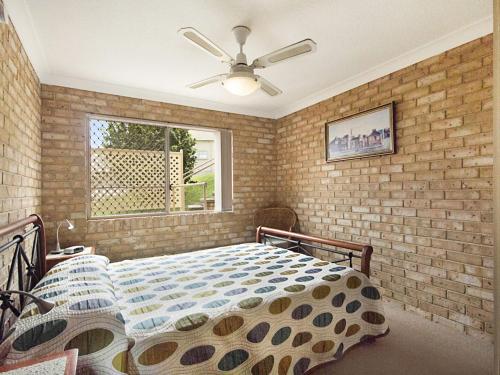 a bedroom with a bed and a brick wall at Tumut Unit 1 in Coolangatta