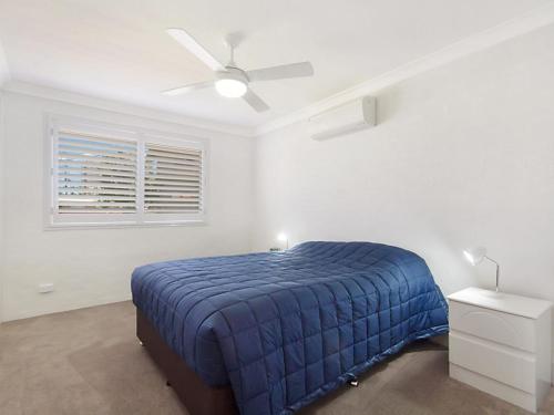 a bedroom with a blue bed and a ceiling fan at Tumut Unit 2 - Balcony with Tweed Harbour Views in Coolangatta