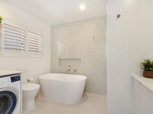 a bathroom with a tub and a toilet and a washing machine at Tumut Unit 2 - Balcony with Tweed Harbour Views in Coolangatta