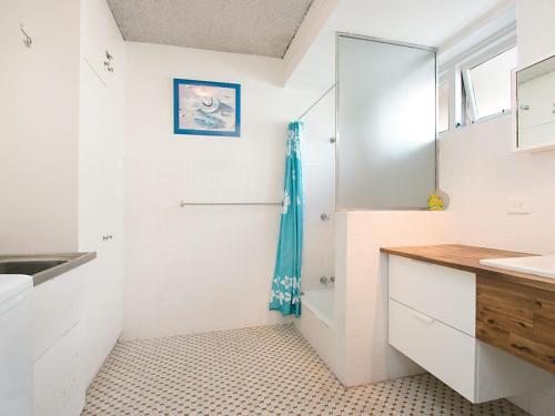 a bathroom with white walls and a sink and a mirror at Tweed Paradise Unit 2 in Coolangatta
