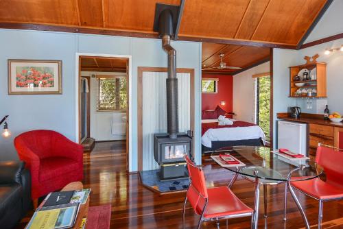 a living room with a wood stove and a bedroom at Rosebrook Cottages in Maleny