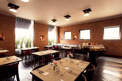 a restaurant with wooden tables and chairs and windows at Mercure Bogota BH Zona Financiera in Bogotá