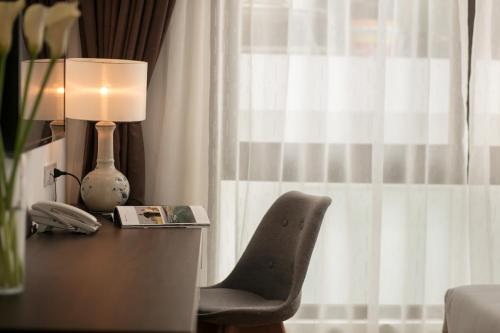 a desk with a lamp and a chair next to a window at Bendecir Hotel & Spa in Hanoi
