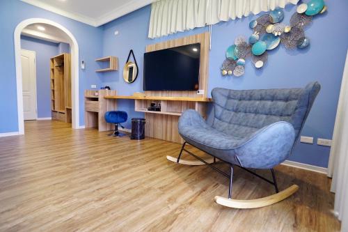 a living room with a blue chair and a television at Dafu Qiandai Manor in Zhuangwei