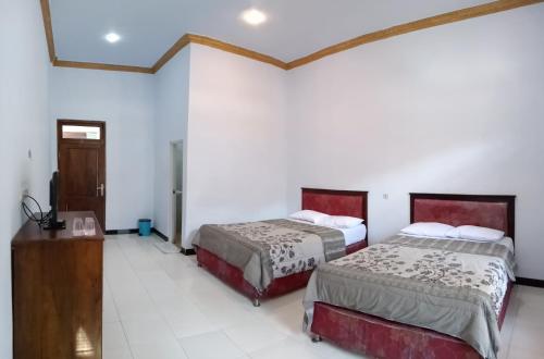 twee bedden in een kamer met witte muren bij Hotel Nadia Bromo in Bromo