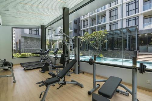 a gym with tread machines and a swimming pool at Arden Hotel and Residence by At Mind in Pattaya Central