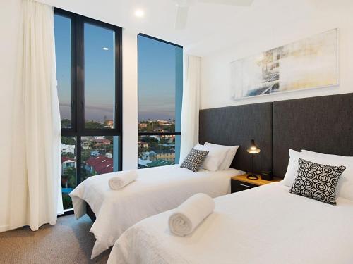 two beds in a hotel room with large windows at Iconic Apartments 704 in Gold Coast