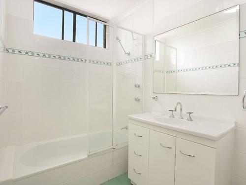 een witte badkamer met een wastafel en een spiegel bij Kirra Gardens Unit 30 in Gold Coast