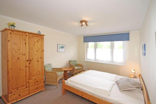 キュールングスボルンにあるDuenengarten-WE-48-Strandlaeufer-9887のベッドルーム1室(ベッド1台付)、木製キャビネットが備わります。
