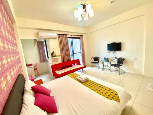 um quarto de hotel com uma cama e um sofá vermelho em Adore Yilan em Luodong