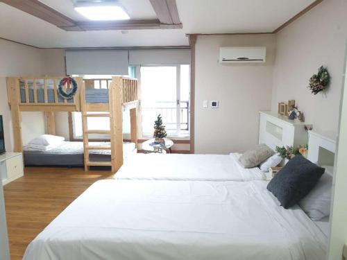 a bedroom with a large white bed and a bunk bed at HY Choi Hostel in Seogwipo