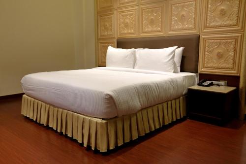 a large bed with white sheets and pillows at Hotel Kasturi Orchid in Pāl