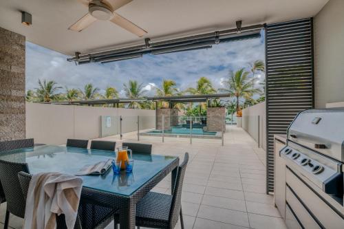 eine Terrasse mit einem blauen Tisch und Stühlen in der Unterkunft Coconut Grove in Port Douglas