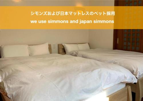 two beds with white sheets in a room at Luxury ocean front house Bay-villa in Matsushima