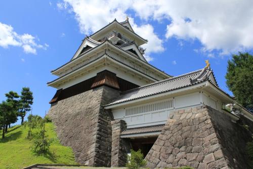 a building with a tower on top of a hill at Senkeien Tsukioka Hotel in Kaminoyama