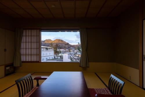 a dining room with a table and chairs and a window at Senkeien Tsukioka Hotel in Kaminoyama