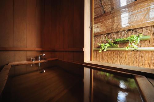 a bathroom with a tub with a plant on the wall at Senkeien Tsukioka Hotel in Kaminoyama