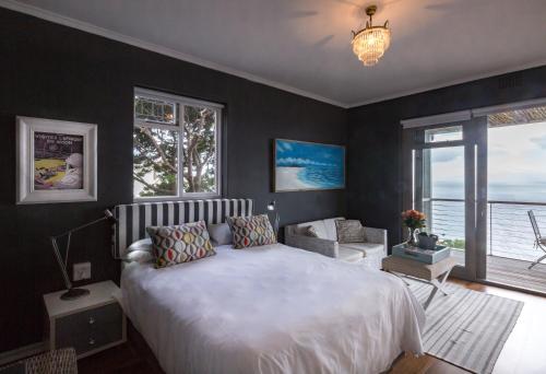 a bedroom with a large bed and a large window at Watercolours Studios in Simonʼs Town