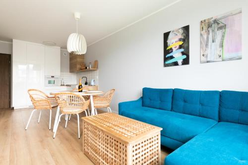a living room with a blue couch and a table at Chill and Sun in Kołobrzeg