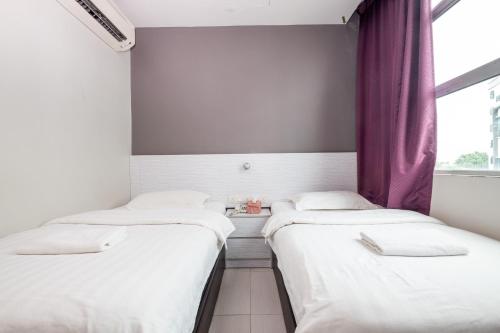 two beds in a room with a window at BG Business Hotel in Bukit Mertajam