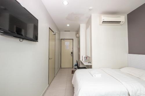 a white bedroom with a bed and a flat screen tv at BG Business Hotel in Bukit Mertajam