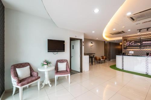 a lobby with two chairs and a table and a tv at BG Business Hotel in Bukit Mertajam