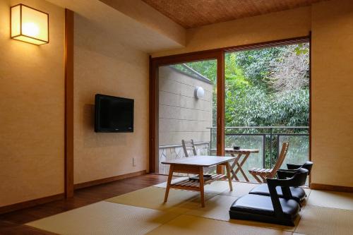 a living room with a table and chairs and a window at Hakuunsou in Yugawara
