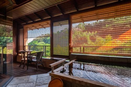 a room with a tub with a table and a window at Hakuunsou in Yugawara