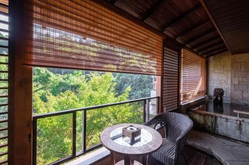 a balcony with a table and chairs and a large window at Hakuunsou in Yugawara