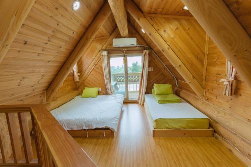 a attic room with two beds and a window at Jungmun Log Pension & Resort in Seogwipo