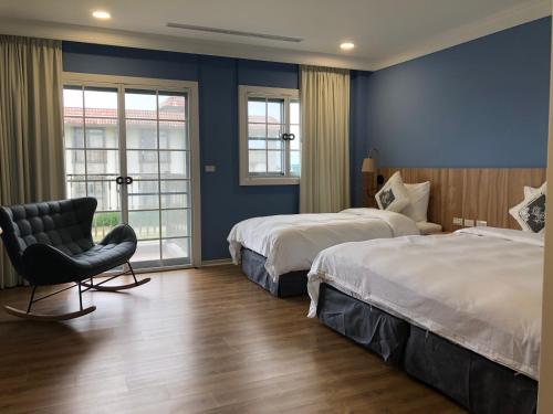 a hotel room with two beds and a chair at Dafu Qiandai Manor in Zhuangwei