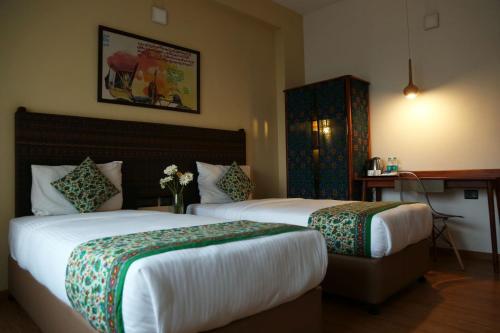 a hotel room with two beds and a desk at Hotel Beebiz Guindy in Chennai