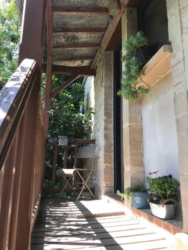 a porch with a chair and a table on a building at Le mas Normand in Ver-sur-Mer