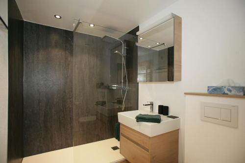 a bathroom with a sink and a shower with a mirror at Apartments Haus Quelle in Leukerbad
