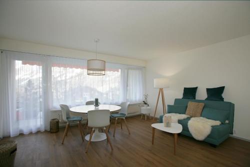 - un salon avec un canapé et une table avec des chaises dans l'établissement Apartments Haus Quelle, à Loèche-les-Bains