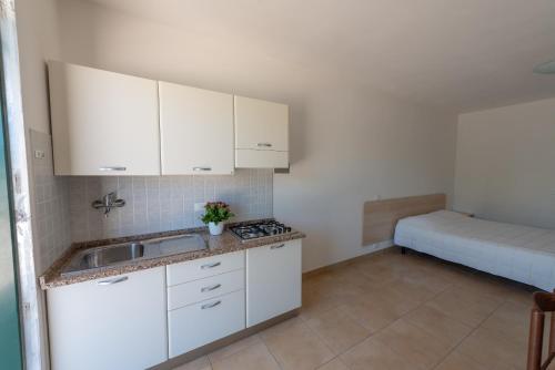 a kitchen with white cabinets and a sink and a bed at Club del Sole Stork Family Collection in Giulianova