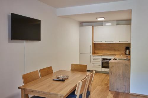 a kitchen with a wooden table with chairs and a television at Kovárna Residence in Pec pod Sněžkou